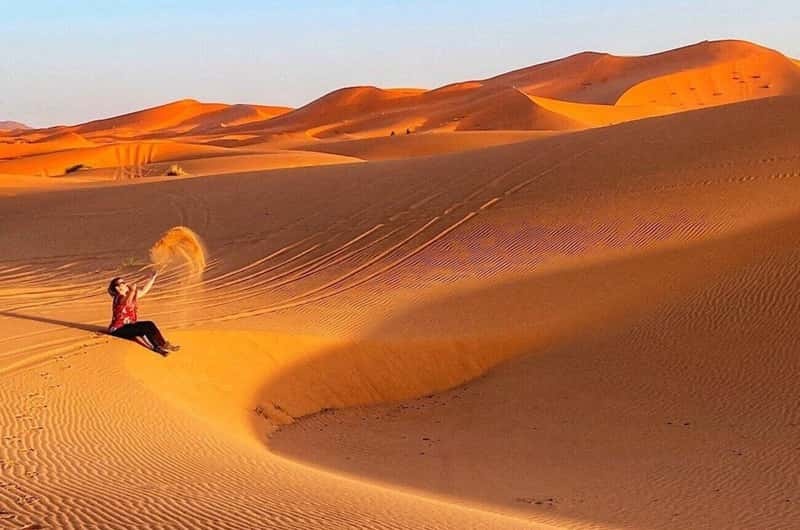 Traveler on a dune ridge at golden hour deciding between Erg Chigaga and Erg Chebbi